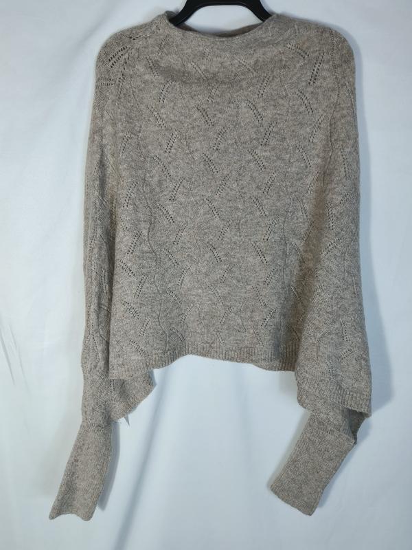 Maglione crop beige a maniche lunghe con lavorazione a maglia pointelle e motivo a rombi, esposto su gruccia. Pullover corto in maglia traforata color beige, ideale per look casual e femminili. Dettaglio del pattern pointelle che conferisce leggerezz