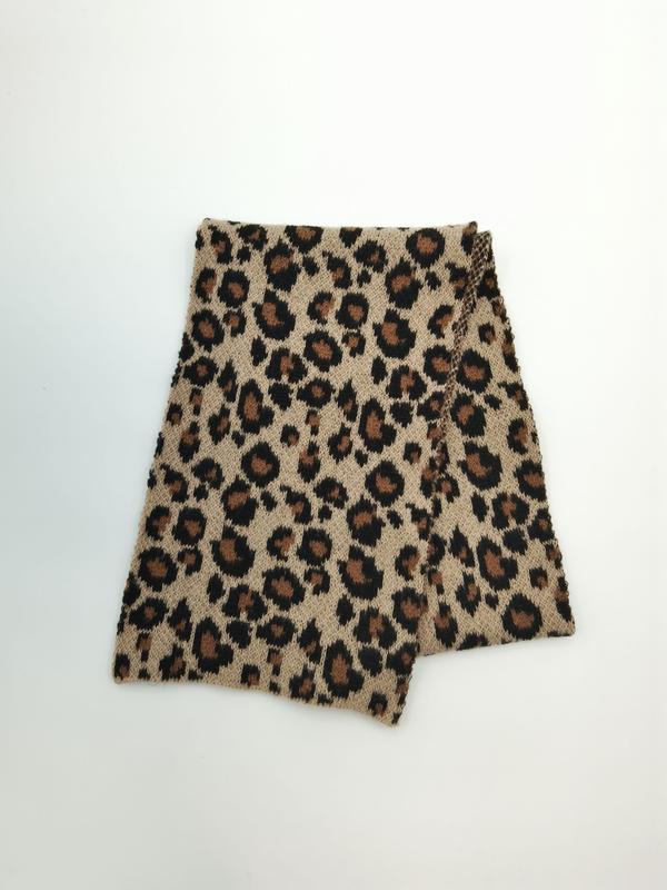 Sciarpa snood in maglia con stampa leopardata beige, marrone e nero, ripiegata su sfondo bianco. Collo invernale lavorato a maglia, motivo animalier elegante, accessorio moda donna caldo e versatile.