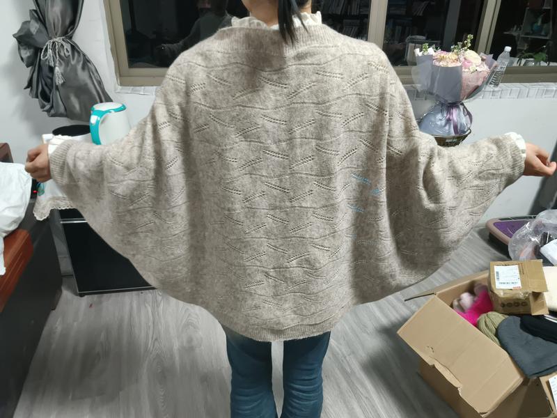 Maglione oversize beige in maglia con maniche a pipistrello e motivo pointelle a rombi, indossato da donna. Capo in morbido filato tricot dal taglio ampio e avvolgente, perfetto per look casual-chic autunnali e invernali. Ideale per rivenditori all'i