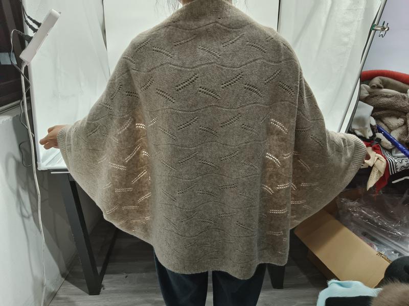 Donna vista da dietro indossa un cardigan oversize in maglia pointelle beige con maniche batwing e dettagli a onde. Il capo in tessuto lavorato a maglia offre un look morbido ed elegante, perfetto per uno stile casual-chic. Colore beige neutro versat