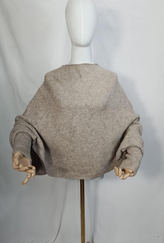 Vista posteriore di maglione oversize a maglia pointelle color avena beige con maniche a palloncino su manichino bianco. Maglione in maglia traforata dal design voluminoso, ideale per look casual e romantici. Tonalità neutre calde per un guardaroba v