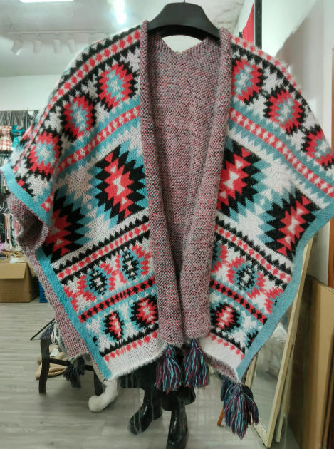 Poncho aperto a maglia con motivo geometrico azteco nei colori rosso, verde acqua, nero e bianco, con dettagli multicolore. Capo in maglia dal design etnico bohémien, ideale come accessorio moda donna versatile. Stile poncho oversize con fantasia jac