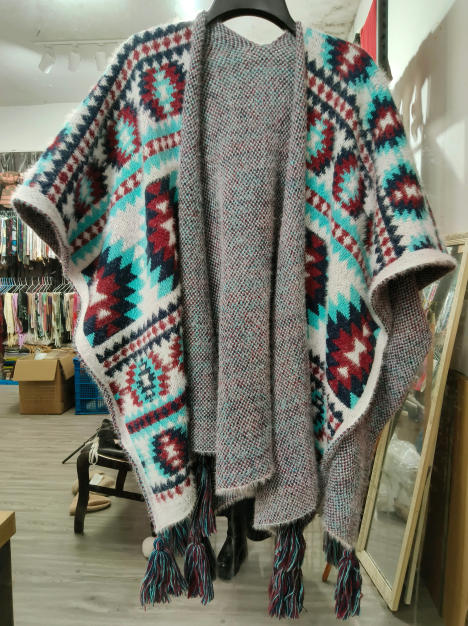 Poncho lavorato a maglia aperto sul davanti con motivo geometrico azteco in verde acqua, bordeaux e bianco, con nappa decorativa. Accessorio moda invernale in maglia jacquard, stile etnico boho-chic. Ideale per la vendita all'ingrosso di abbigliament