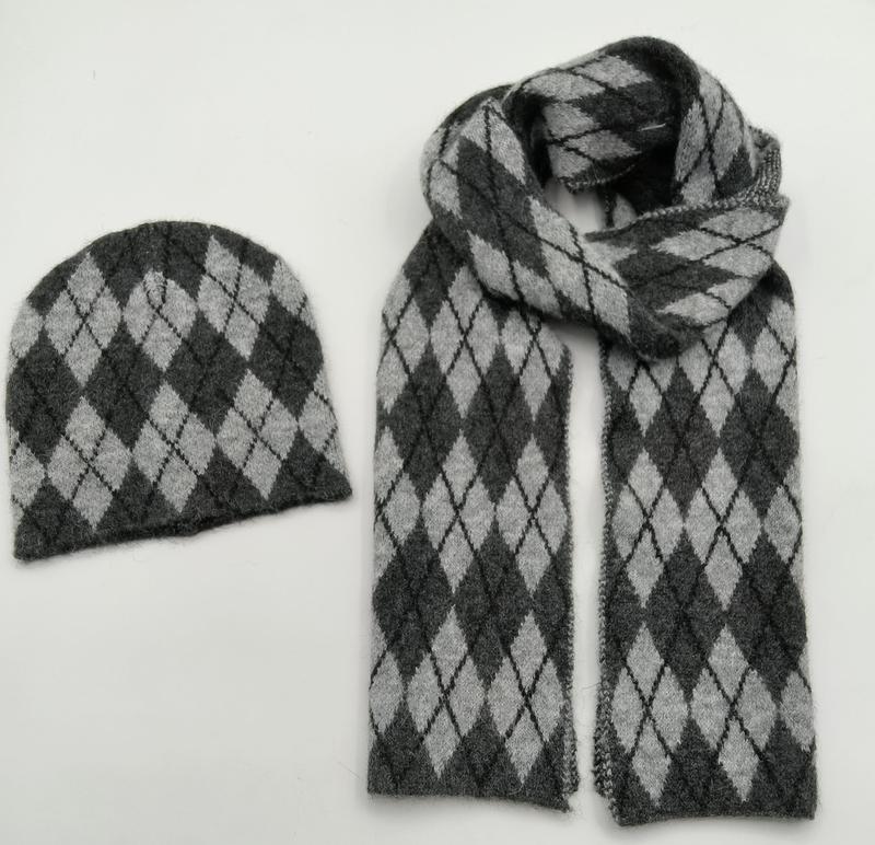 Set coordinato berretto e sciarpa lunga in maglia argyle, nei toni grigio scuro e grigio chiaro. Accessori invernali unisex in filato morbido con motivo losanghe classico, ideali per la vendita all'ingrosso. Foto flat lay su sfondo bianco. Product 97